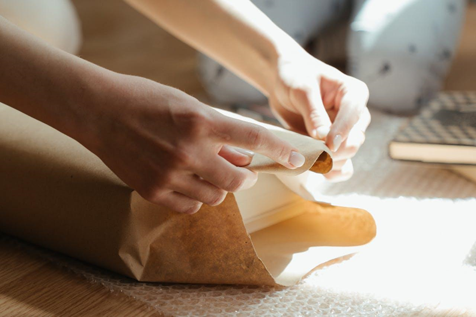 A person packing a book using paper.